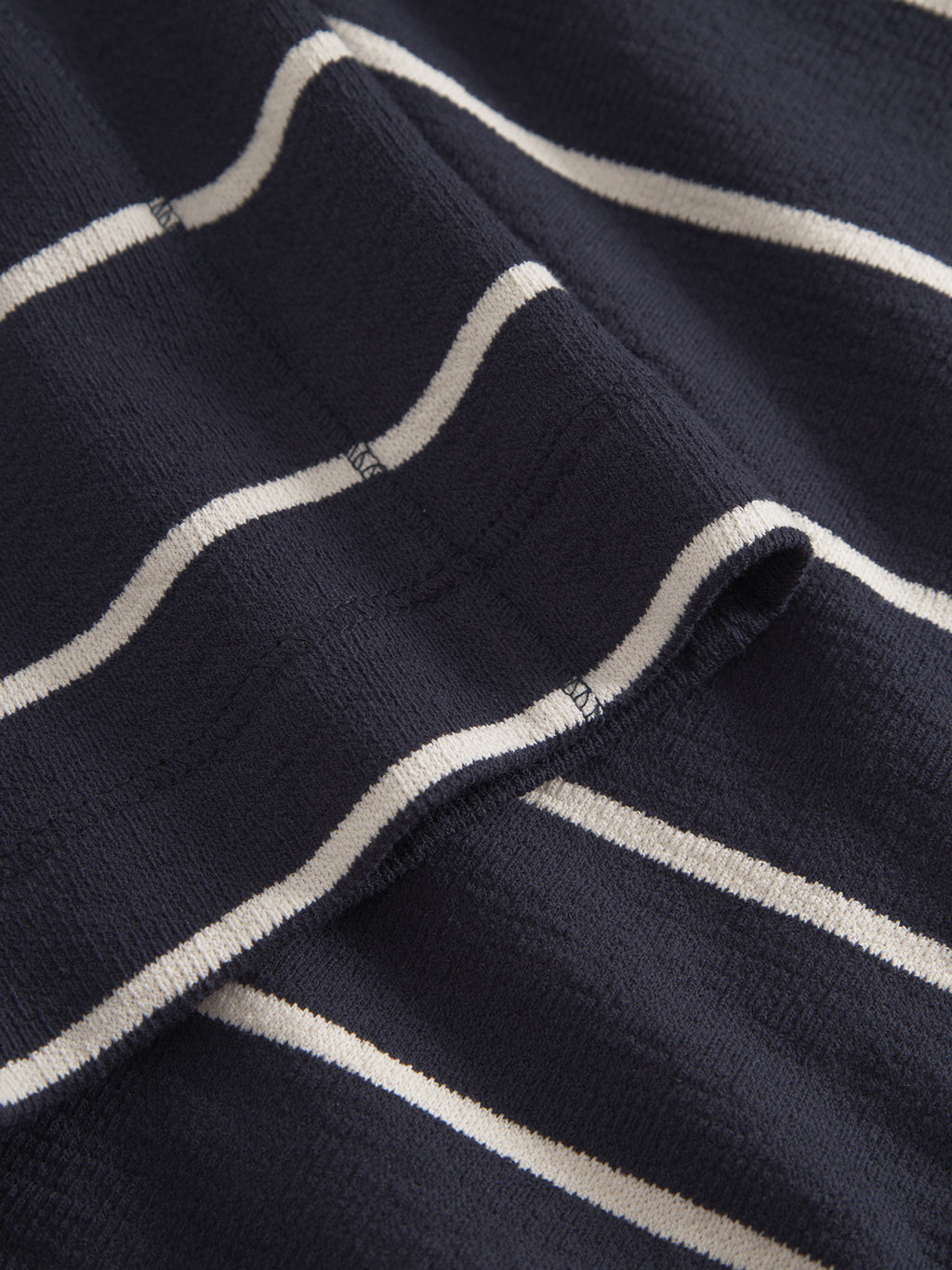 Close-up of Gabba’s Dune Crepe Stripes SS GOTS - Navy Stripe: navy blue organic cotton with white horizontal stripes, featuring textured material and neat stitching—ideal for a classic fit t-shirt.