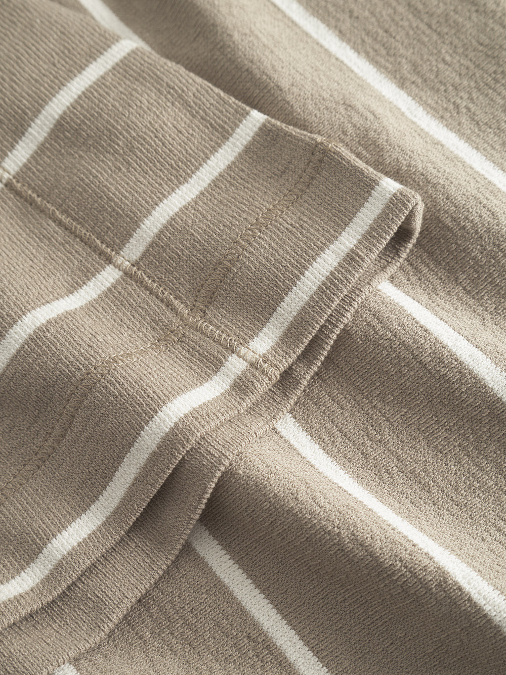 Close-up of Gabba’s Dune Crepe Stripes SS GOTS - Brown Stripe t-shirt, made from GOTS-certified organic cotton. The image highlights its beige fabric with white stripes, visible seam, soft texture, and detailed stitching.
