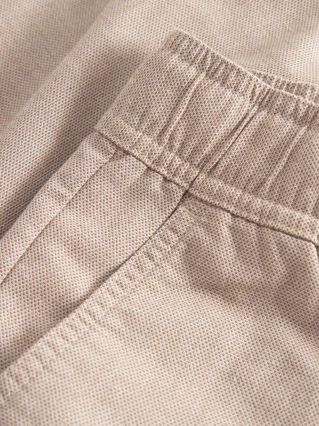 Close-up of Gabba Coz Belt Carre Shorts in Sand, showcasing a pocket, elastic waistband, and unique belt strap. The subtle dotted texture delivers premium comfort.