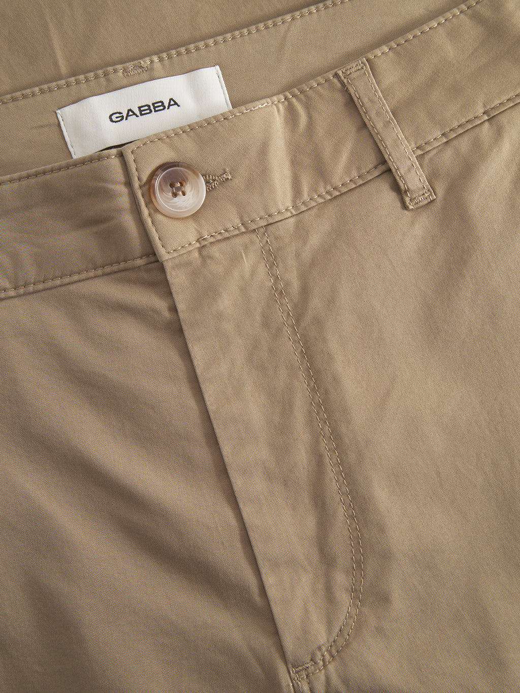 Close-up of Gabba’s Monza Unite - Sand pants in beige, featuring a single button, visible stitching, relaxed straight fit, classic silhouette, and a white “Gabba” label sewn inside the waistband.
