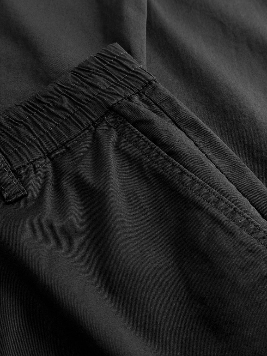 Close-up of Gabba’s Monza Unite - Black: a pair of relaxed straight pants with an elastic waistband, side pocket with visible stitching, and a classic silhouette in smooth, slightly reflective fabric.