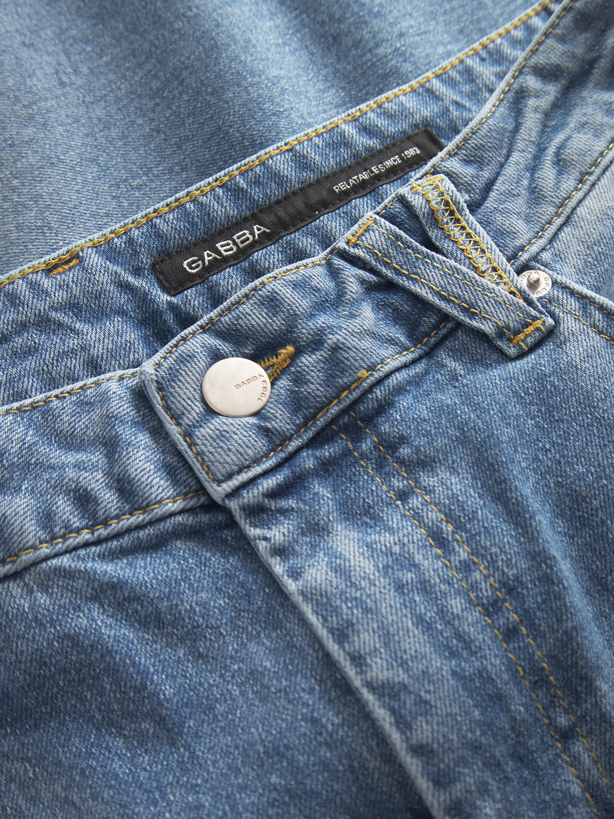 Close-up of Gabbas Marc 5poc - Mid Blue Denim jeans, featuring a modern classic look with visible stitching, a metal button engraved with Gabba, and a brand label on the waistband. These regular fit jeans display a classic blue hue with subtle fading and texture details.