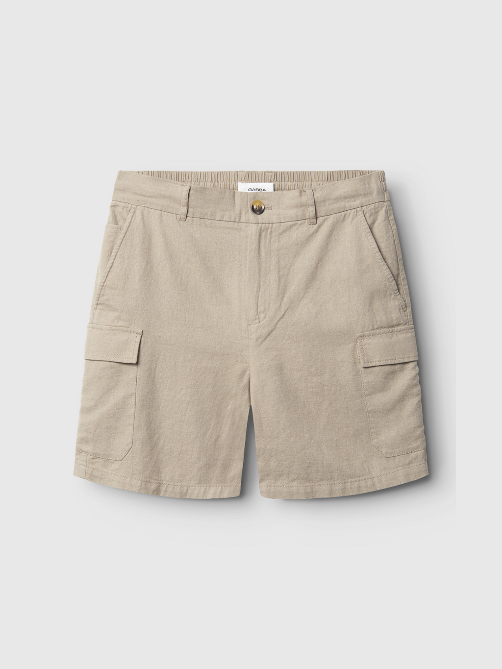 The Gabba Alfa Cargo Lino - Sand Plaza shorts are made from durable, breathable fabric with an elastic waistband, belt loops, button closure, side pockets, and two large thigh flap pockets, shown on a plain light background.