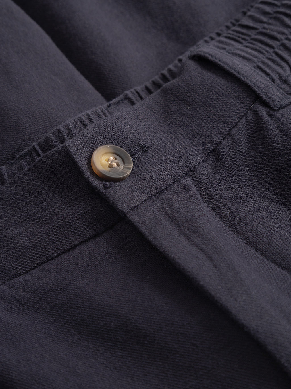 Close-up of Gabba Alfa Cargo Lino pants in Night Sky, featuring a button and part of an elastic waistband with visible stitching details.