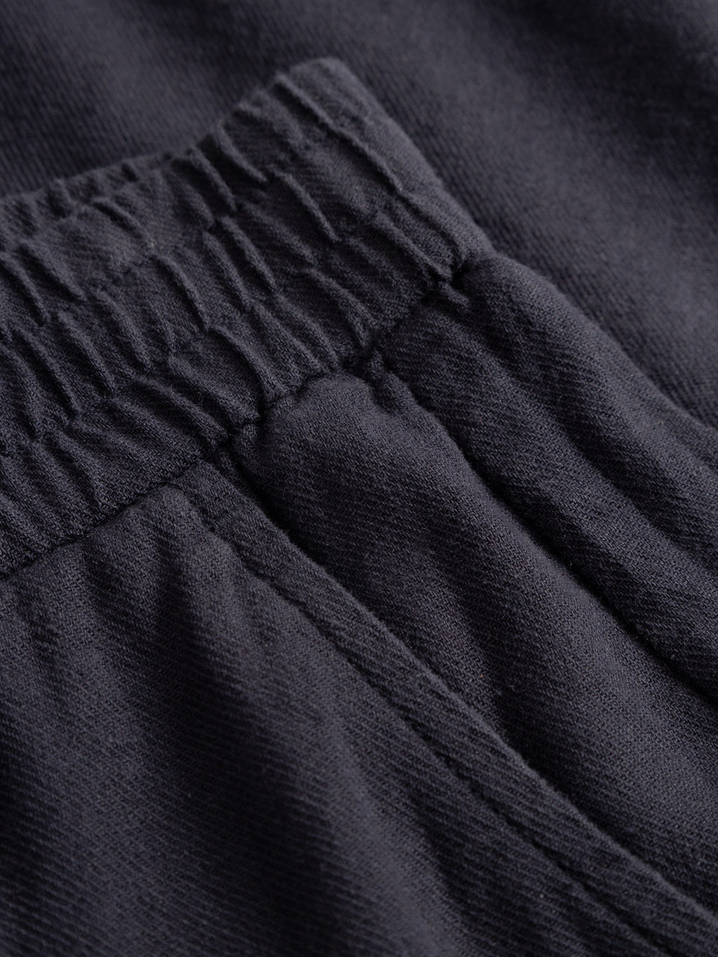 Close-up view of the waistband and pocket area of Gabbas Alfa Cargo Lino sweatpants in Night Sky, featuring dark-colored, textured fabric with an elastic band.