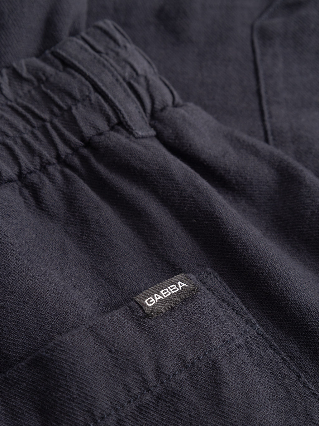 Close-up of Gabba Alfa Cargo Lino pants in Night Sky, featuring an elastic waistband and a small black GABBA tag sewn onto the fabric.