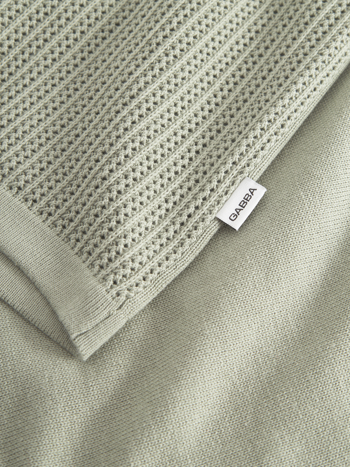 A close-up of the textured fabric from Gabbas Geno Resort SS - Light Green, featuring a premium knit pattern in 100% cotton. The fabric is neatly folded on a flat surface, perfect for crafting a luxurious knit cardigan.