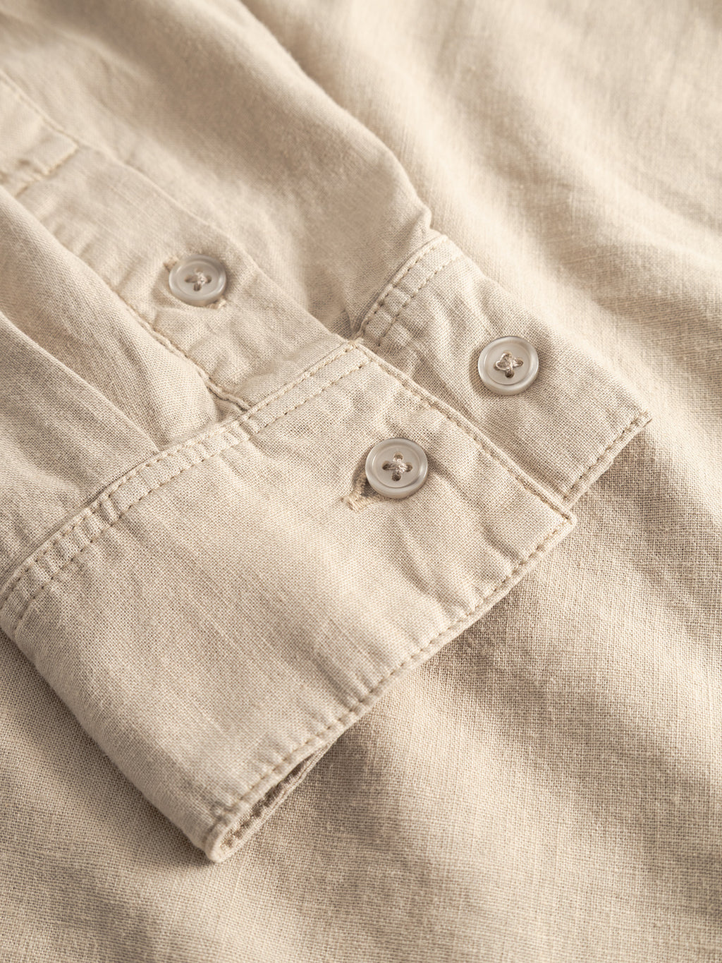 Close-up of the Sven Reg Lino LS - Sand Plaza shirt by Gabba, highlighting the beige linen sleeve with textured stitching and two white buttons on the cuff.