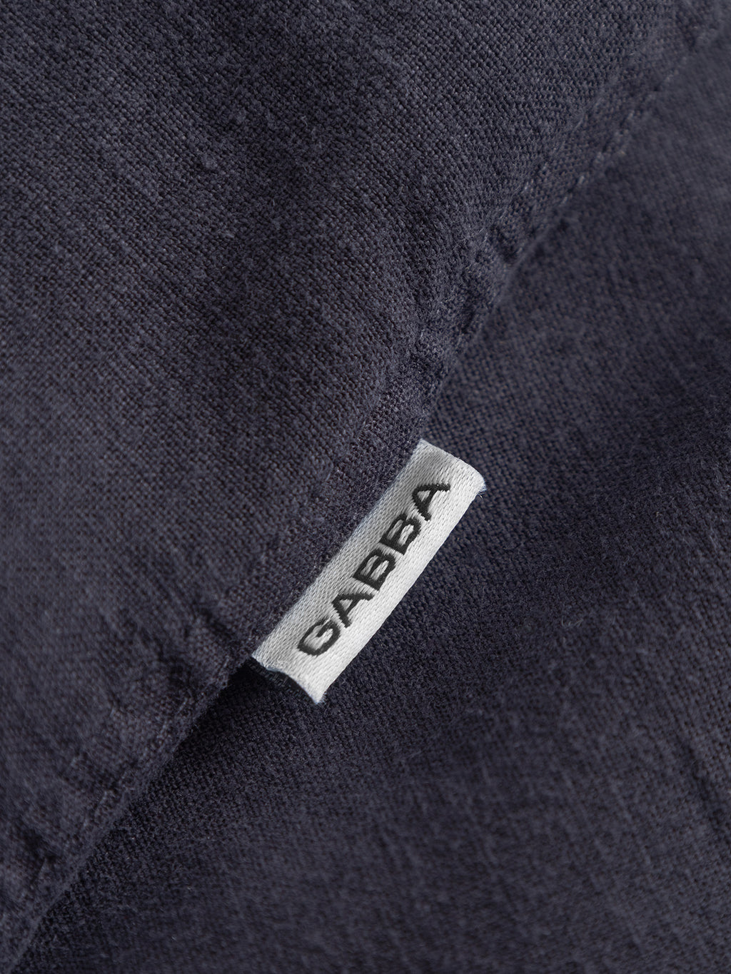 Close-up of the dark Sven Reg Lino Mand LS - Night Sky fabric with a small white tag sewn into the seam, displaying the Gabba brand name in bold black letters.