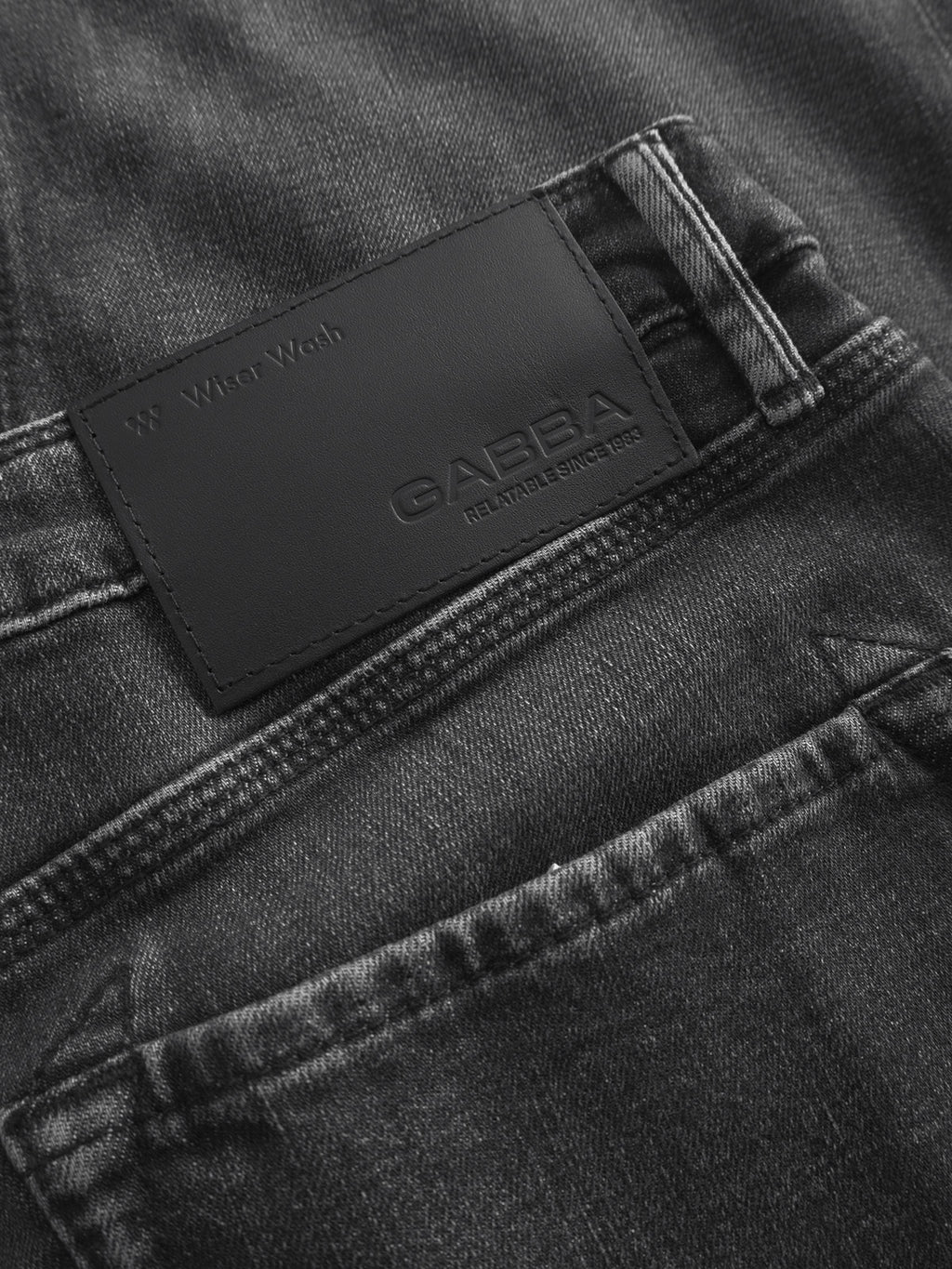 Close-up of the back pocket on Gabba’s Carl Dlak - Black Denim jeans, featuring a black leather patch embossed with “Gabba” and “Reliable Since 1983.”.