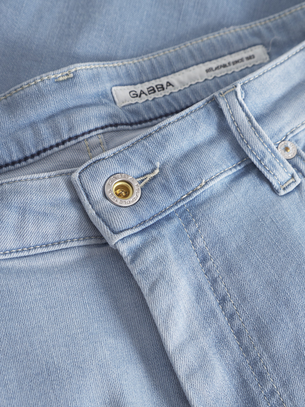 Close-up of Gabba Markus K3987 Shorts in light blue denim, featuring a labeled waistband, belt loops, metal button, and part of the zipper—offering a comfortable fit perfect for stylish denim short seekers.