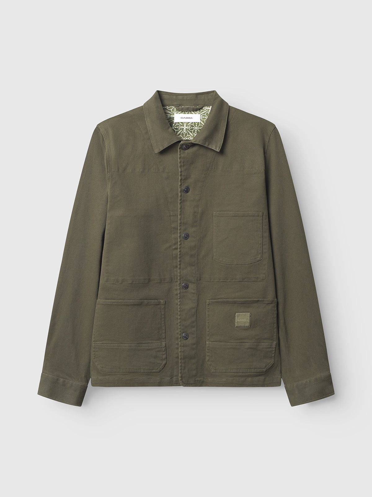 The Gabba Beta Twill - Army is an olive green workwear-inspired overshirt with a collar, button-down front, and three patch pockets. Made from garment dyed twill, it has a patterned inside collar lining and is shown against a plain light background.