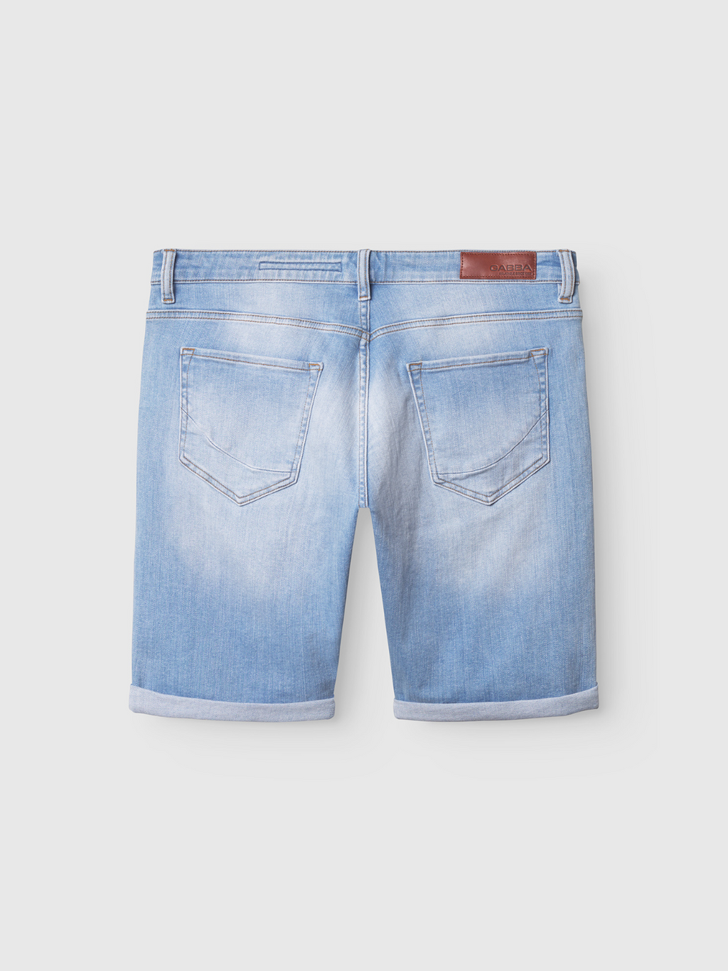 The Gabba Markus Selvedge Shorts Limited in light blue denim feature two back pockets, rolled hems, stitching accents, and a brown leather patch on the waistband for comfort.