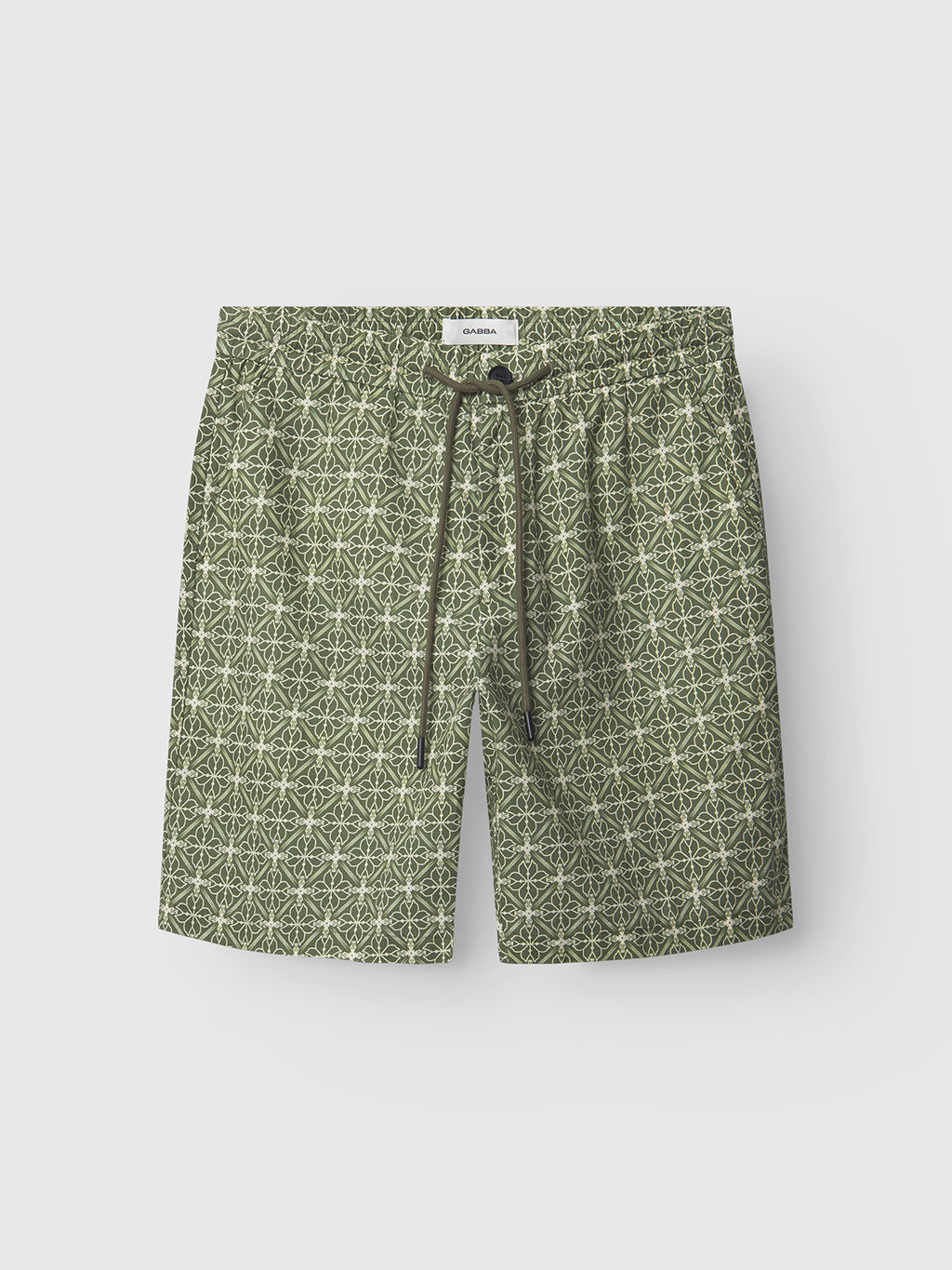 The Gabba Tommi AOP - Khaki are green 100% cotton swim shorts featuring a geometric star pattern, elastic waistband, and dark green drawstring—premium design for style and comfort, shown on a plain light background.