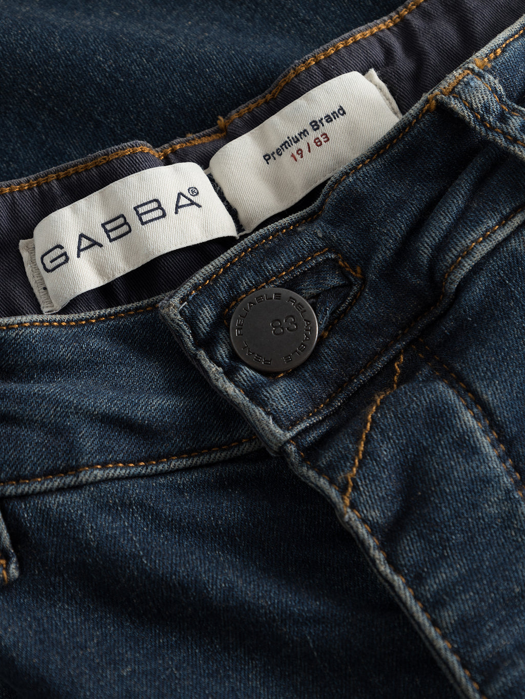 Close-up of GABrey K3606 Mid Blue Jeans by GABBA, showcasing “GABBA” and “Premium Brand” labels on the waistband, metal button with “38” and “RELIABLE WEAR TROUSERS,” orange stitching, and a relaxed mid-blue denim look.