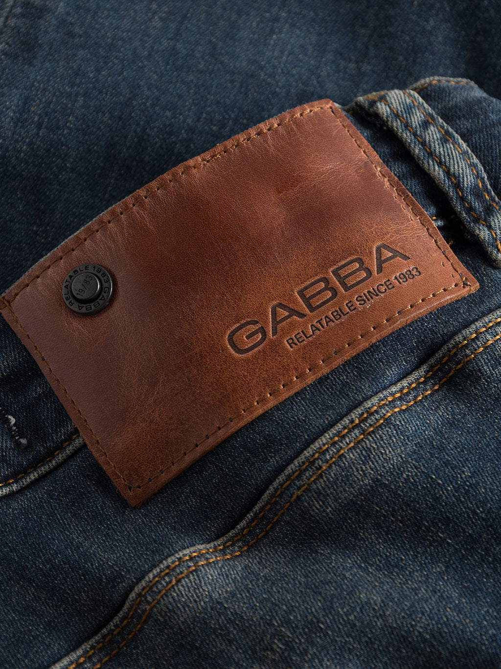 Close-up of a brown leather patch with GABBA branding on GABrey K3606 Mid Blue Jeans in mid-blue denim, featuring detailed stitching and a metal button—ideal for elevating your casual style.