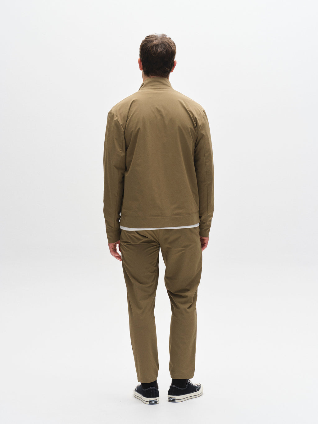 A man faces away, wearing the Gabba GABnik Tech - Army matching tan jacket and pants with black sneakers, set against a plain white background.