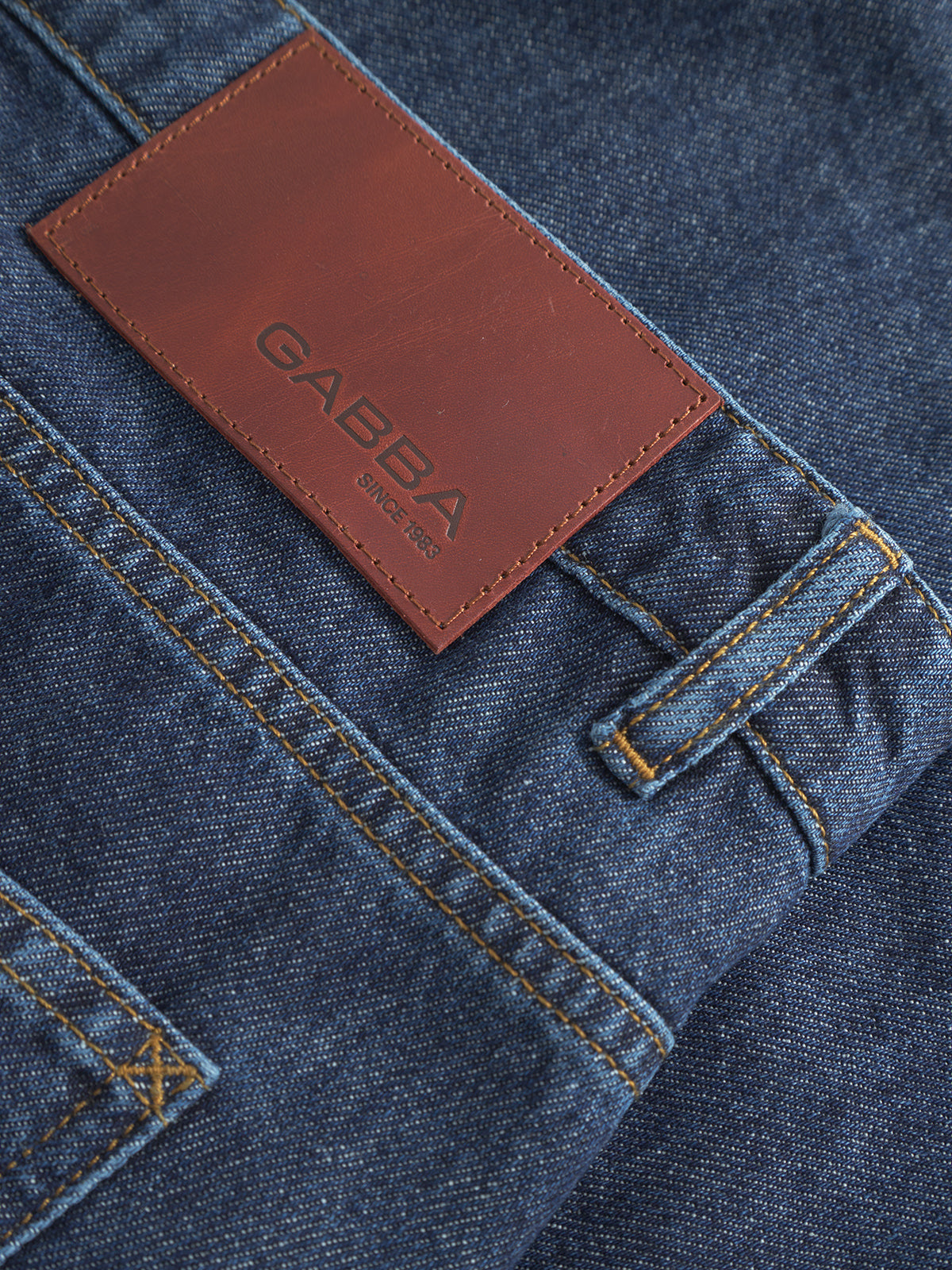 Close-up of blue Gabba Ugo Cargo Fone jeans with a brown leather patch showing the brand name and Since 1983 in black letters. The loose-fit design features visible stitching and belt loops, inspired by classic workwear aesthetics.