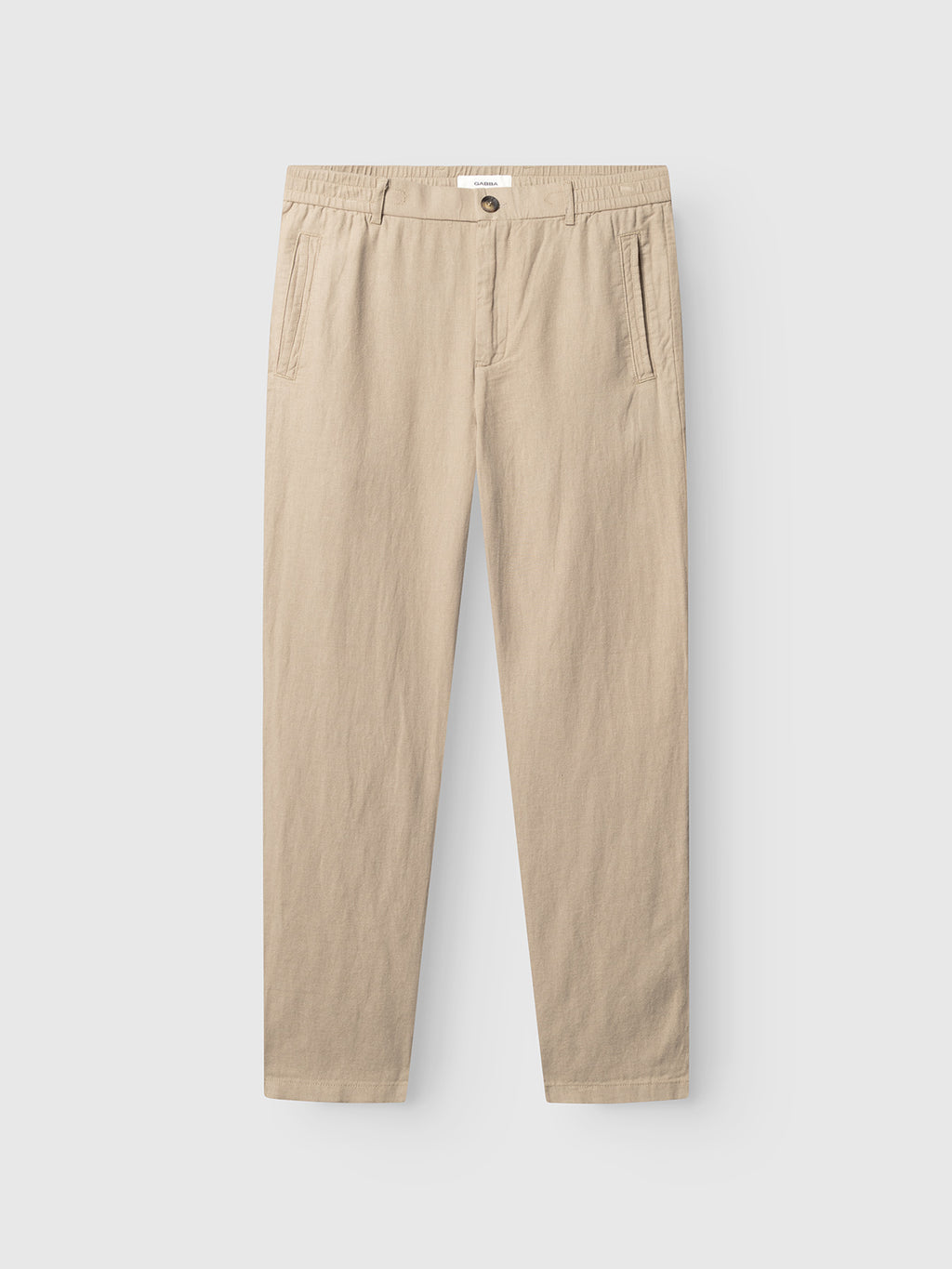 The Monza Lino Cropped - Sand Plaza pants by Gabba feature an elastic waistband, front button closure, side pockets, and a relaxed fit for comfort. Shown flat on a white background in a beige shade.