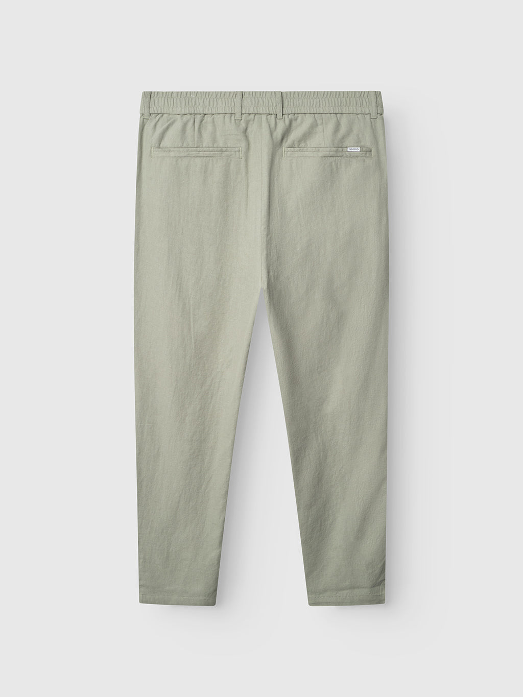 The Gabba Monza Lino Cropped trousers in light green are shown from the back, featuring an elastic waistband and two welt pockets. These relaxed straight pants offer comfort and timeless style against a plain white background.