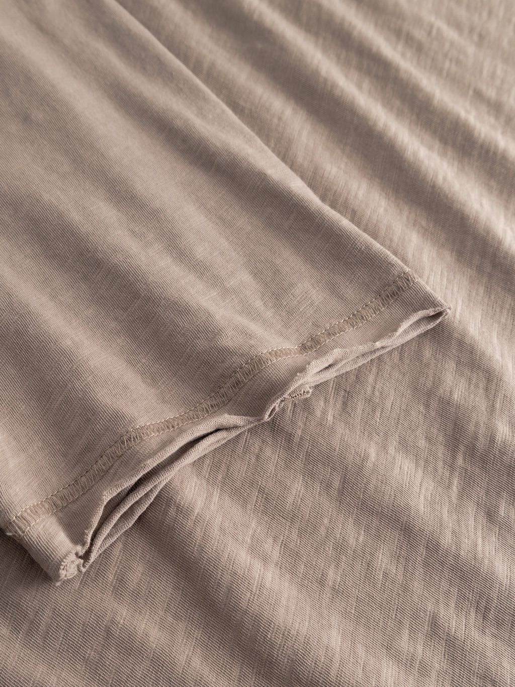 A close-up of the GABkostant New SS - Fungi by Gabba, featuring light brown, soft slub fabric with visible stitching along the sleeve edge and a slightly wrinkled texture.