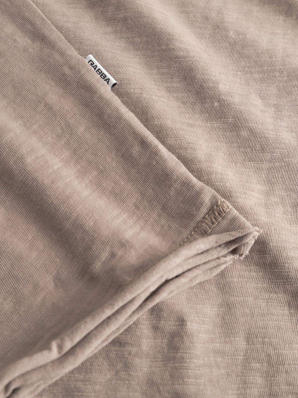 A close-up of the light brown, textured GABkostant New SS - Fungi t-shirt fabric by Gabba, neatly folded with a white label showing 