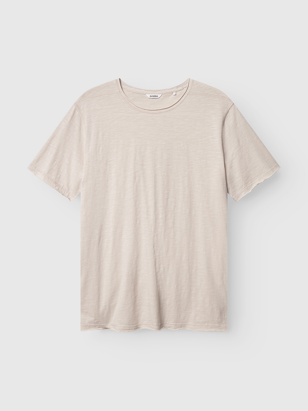 The Gabba Kostant New SS t-shirt in White Almond features a regular fit, short sleeves, and crew neck. Its subtle slub texture offers understated style. Displayed here against a white background.