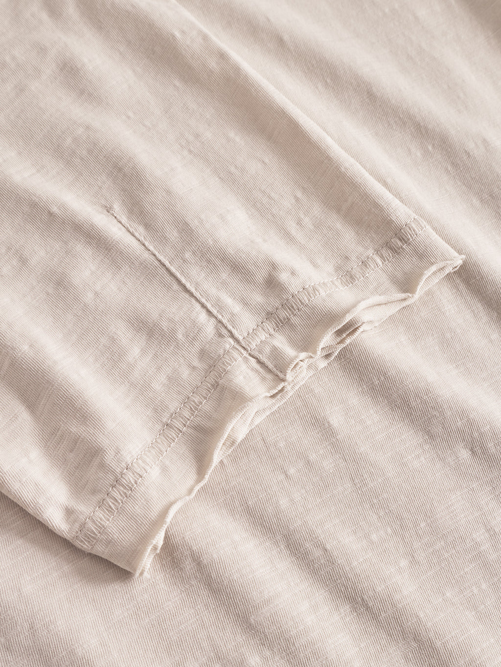 Close-up of Gabbas Kostant New SS in White Almond, highlighting the sleeve and side seam with visible stitching and a soft, light slub linen texture.