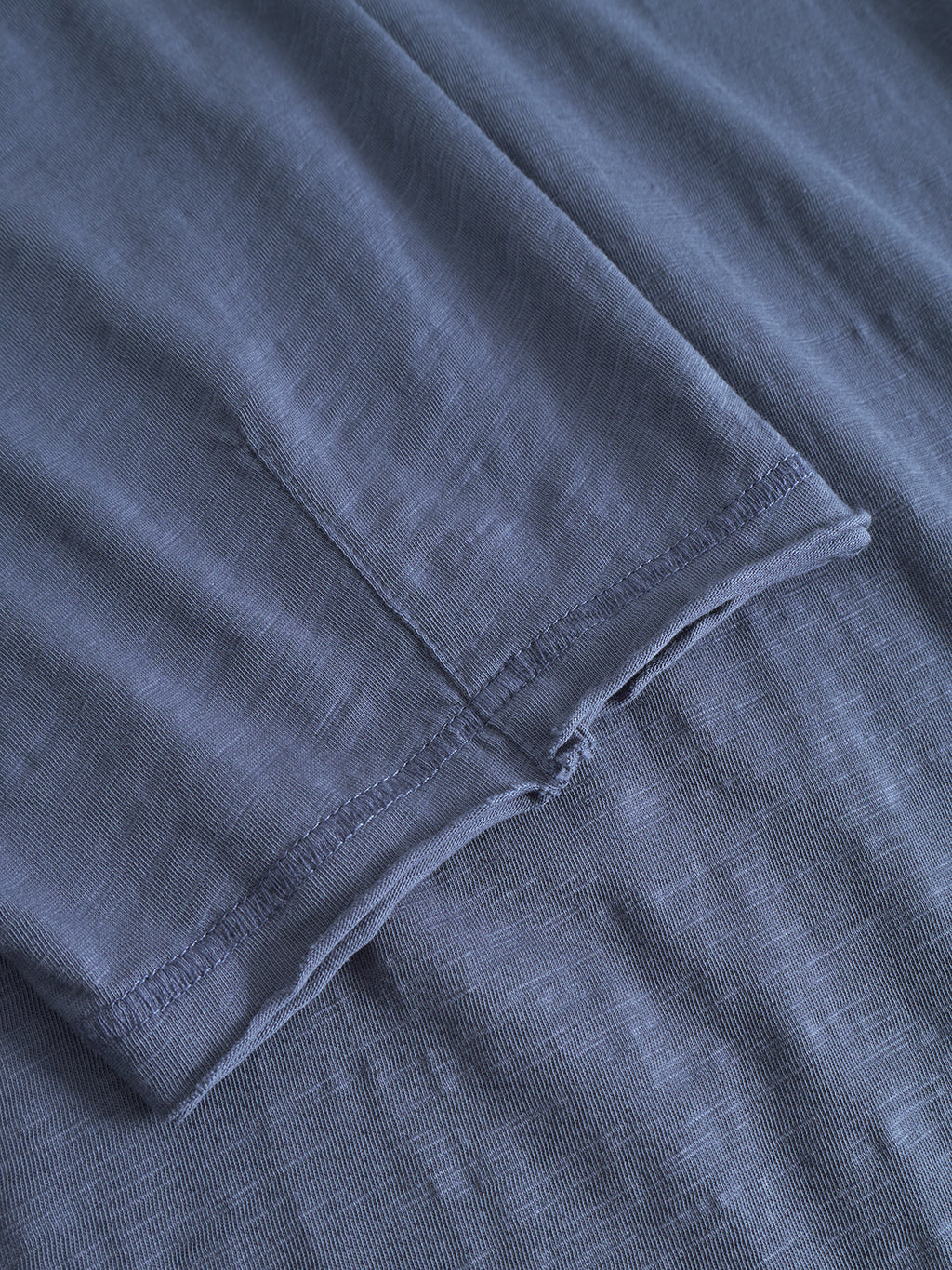 Close-up of the Kostant New SS - Vintage Indigo by Gabba, highlighting the textured indigo cotton slub fabric with visible seams, stitching, and edge hem.