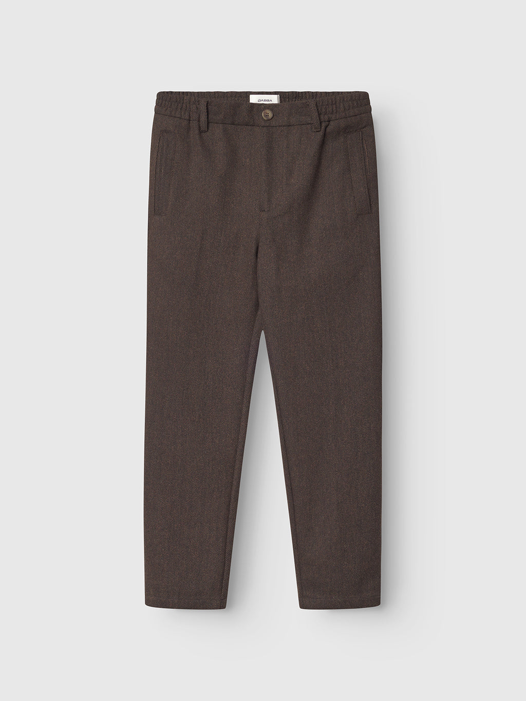 The Gabba Monza Wook - Brown: tailored trousers featuring an elastic waistband, front button closure, and side pockets, shown laid flat on a white background.