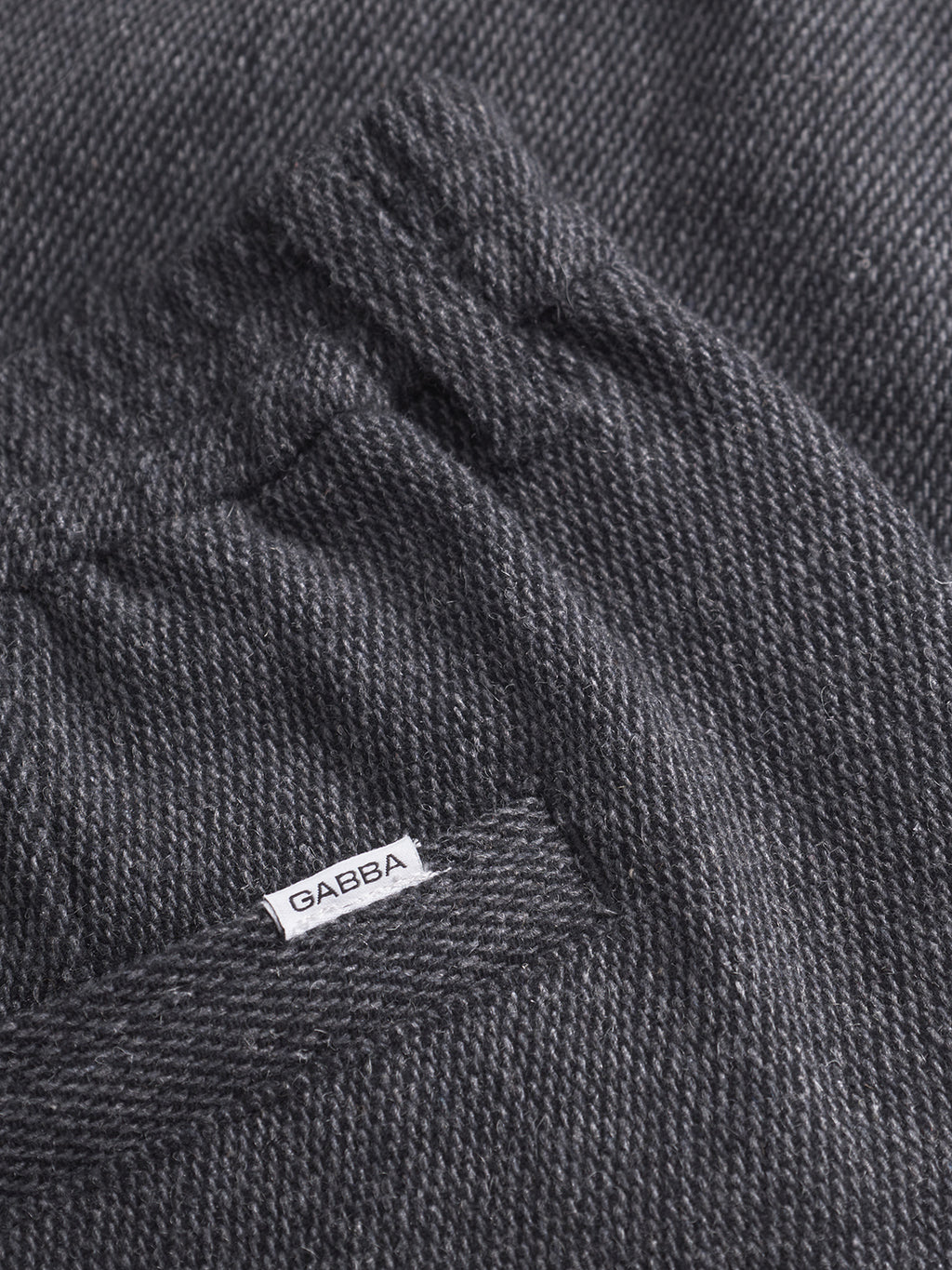Close-up of a pocket on Gabba Monza Wook - Dk. Grey trousers featuring dark gray textured fabric, an elasticated waistband, and a small white Gabba label sewn above the pocket opening.