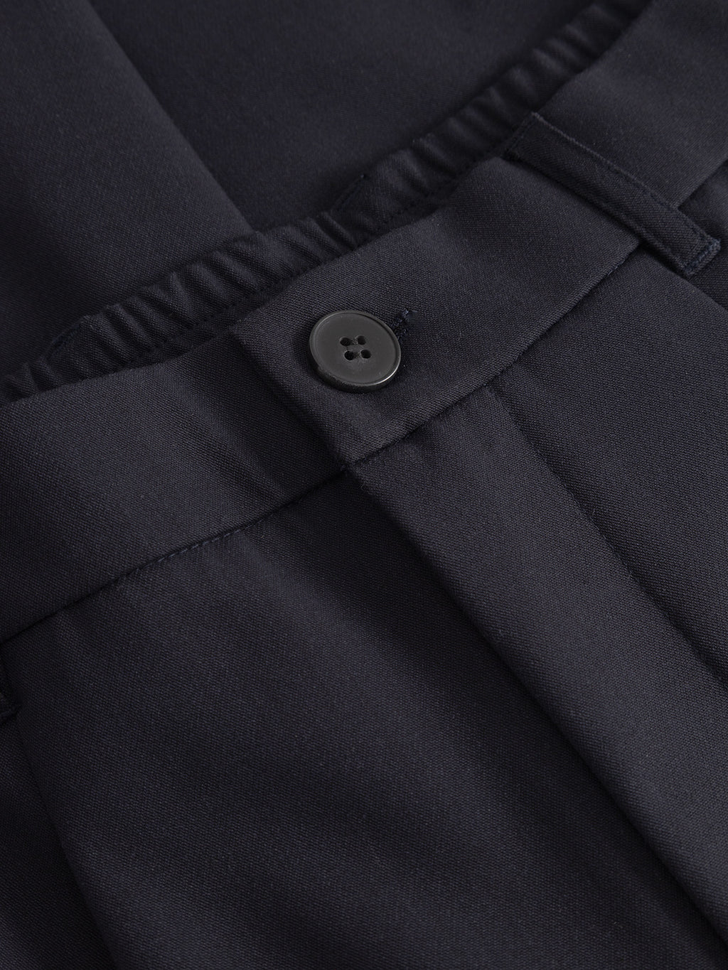 Close-up of Gabbas Napoli 19 Phin GRS - Navy tailored pants in recycled wool-blend, featuring an elastic waistband section, single black button, and belt loop. The smooth, matte fabric offers a refined modern staple.