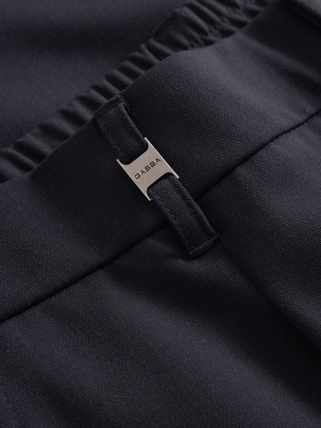 Close-up of Gabba’s Napoli 19 Phin GRS tailored pants in navy recycled wool-blend, featuring an elastic waistband and a metallic belt loop tag engraved “GABBA”—a modern essential.
