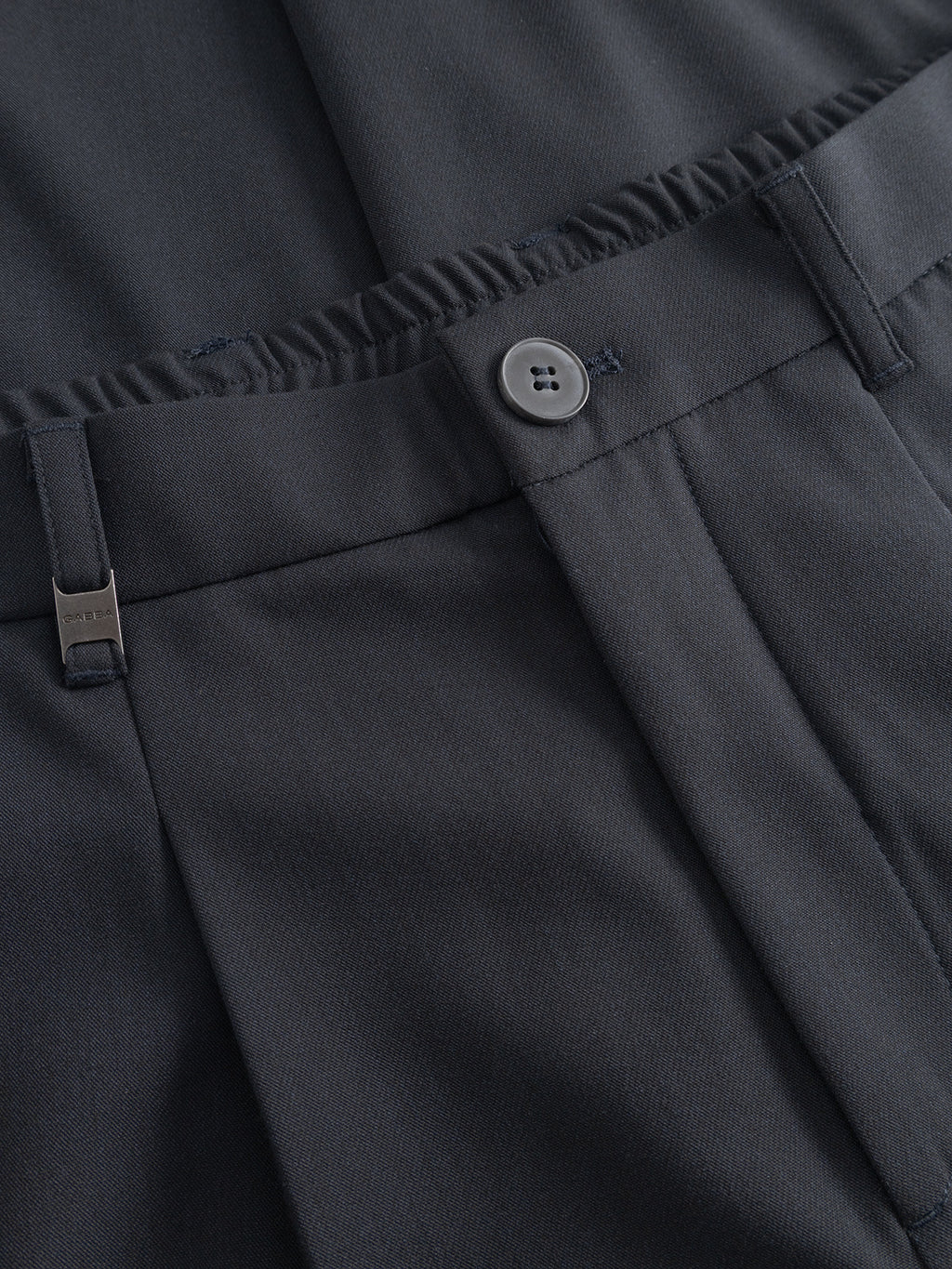 Close-up of the waistband on Gabba’s GABnapoli 19 Phin GRS - Blue Black chino trousers, highlighting the button closure, belt loop, metal clasp, and partially hidden back elastic. The wool blend fabric looks smooth and tailored.