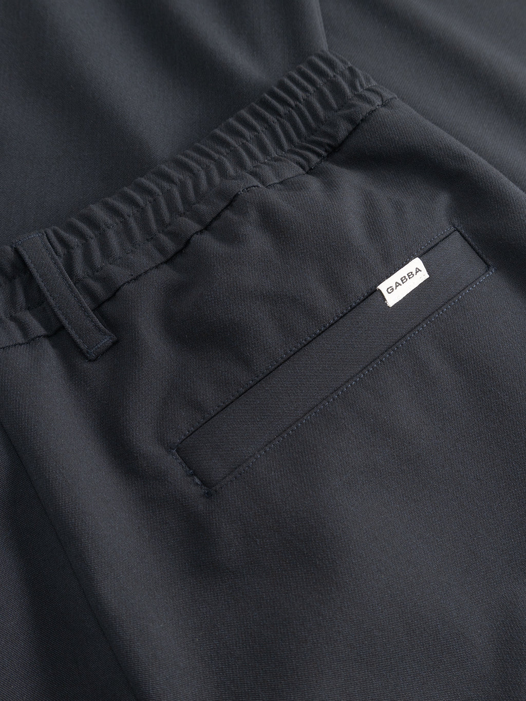 Close-up of Gabba GABnapoli 19 Phin GRS chino pants in blue black wool blend, featuring an elastic waistband, belt loop, and a back welt pocket with a small white Gabba label.