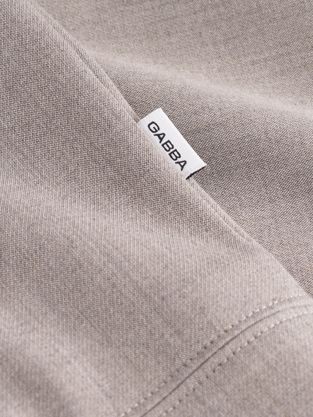 Close-up of sand-colored fabric from the Gabba GABnik Phin GRS jacket, showing visible stitching and a small white label with 