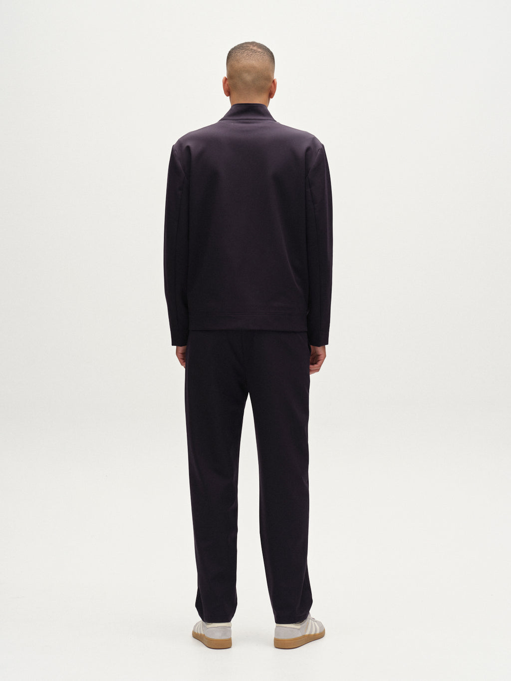 A person faces away from the camera, wearing the Gabba Nik Bascu - Navy jacket and matching pants, paired with light-colored shoes, set against a plain white background.
