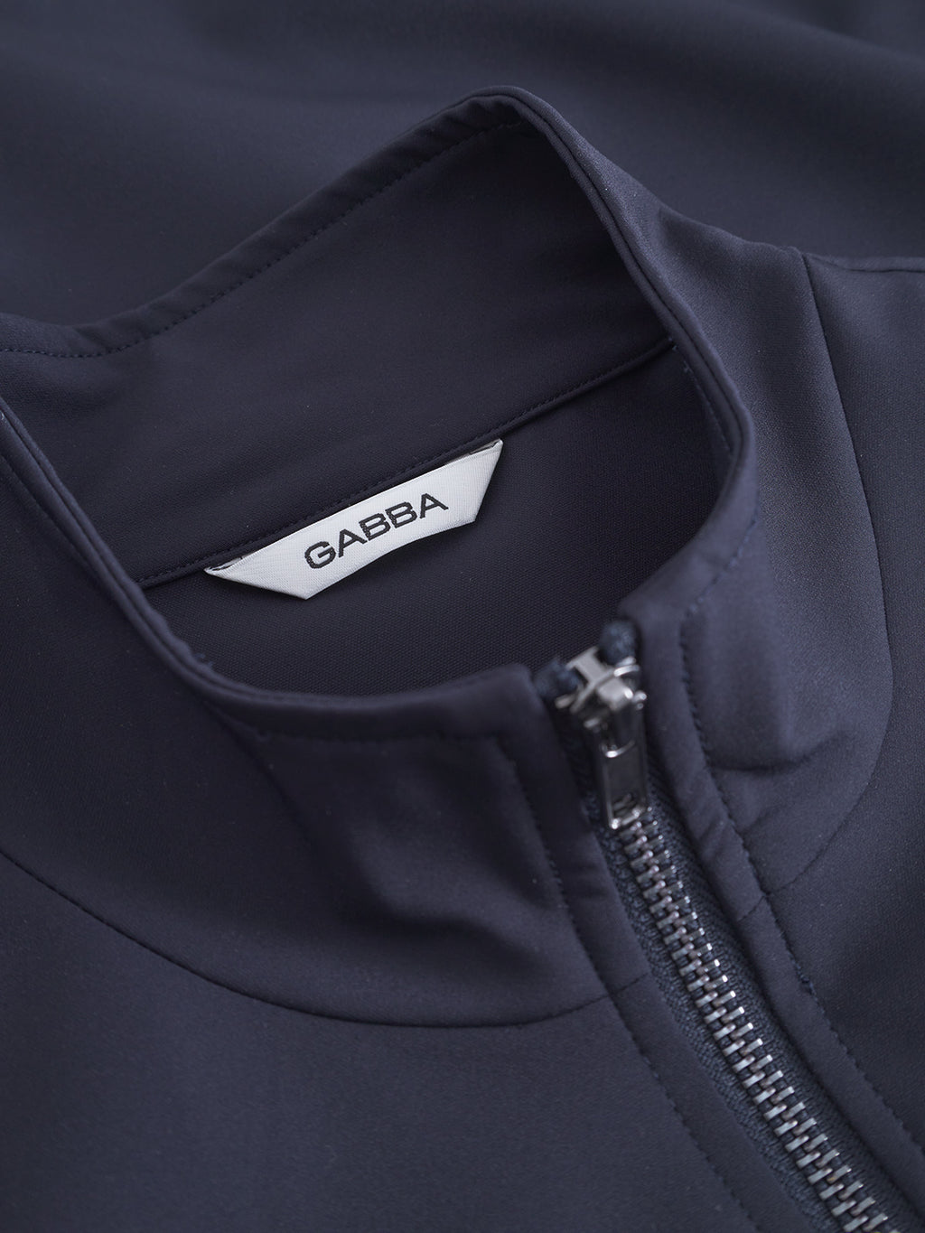 Close-up of the Nik Bascu jacket by Gabba in navy, featuring a lightweight design, stand collar, and a visible white inner label branded Gabba.