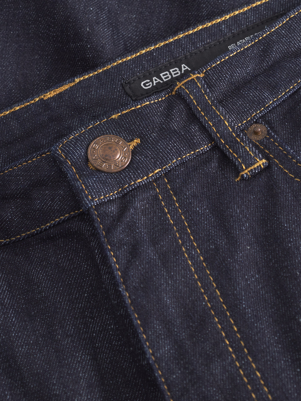 Close-up of Gabba Noah Self - Dark Blue Denim jeans featuring visible orange stitching, a metal button, a rivet, and a black Gabba label sewn onto the waistband.