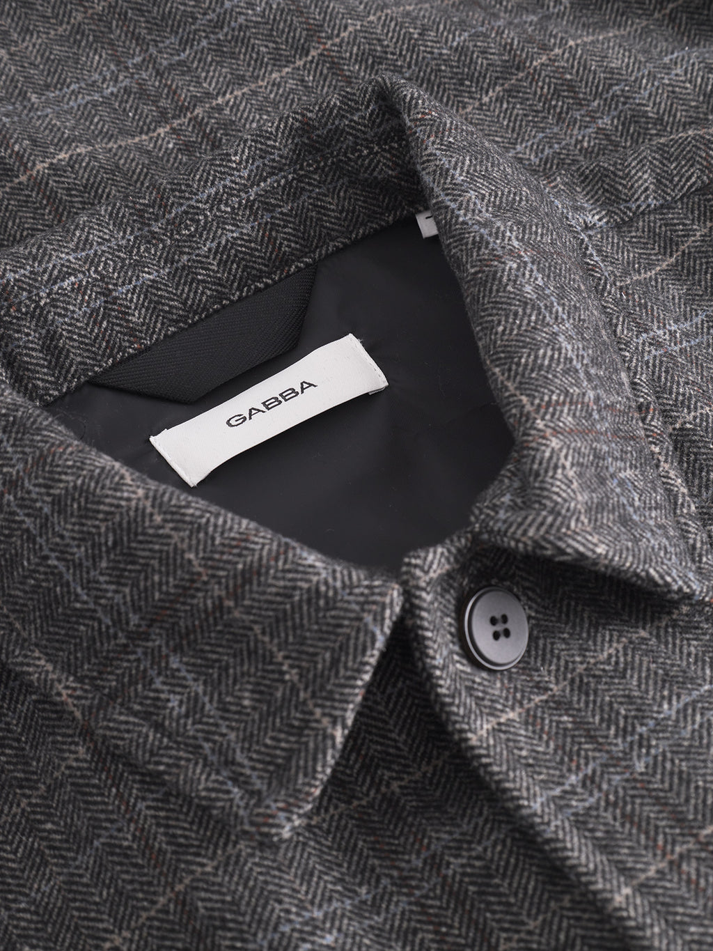 Close-up of the Gabba Flap Tishi - Brown Check overshirt featuring a brown check pattern, black button on the front placket, visible inner lining, and Gabba label—an ideal mens layering piece.