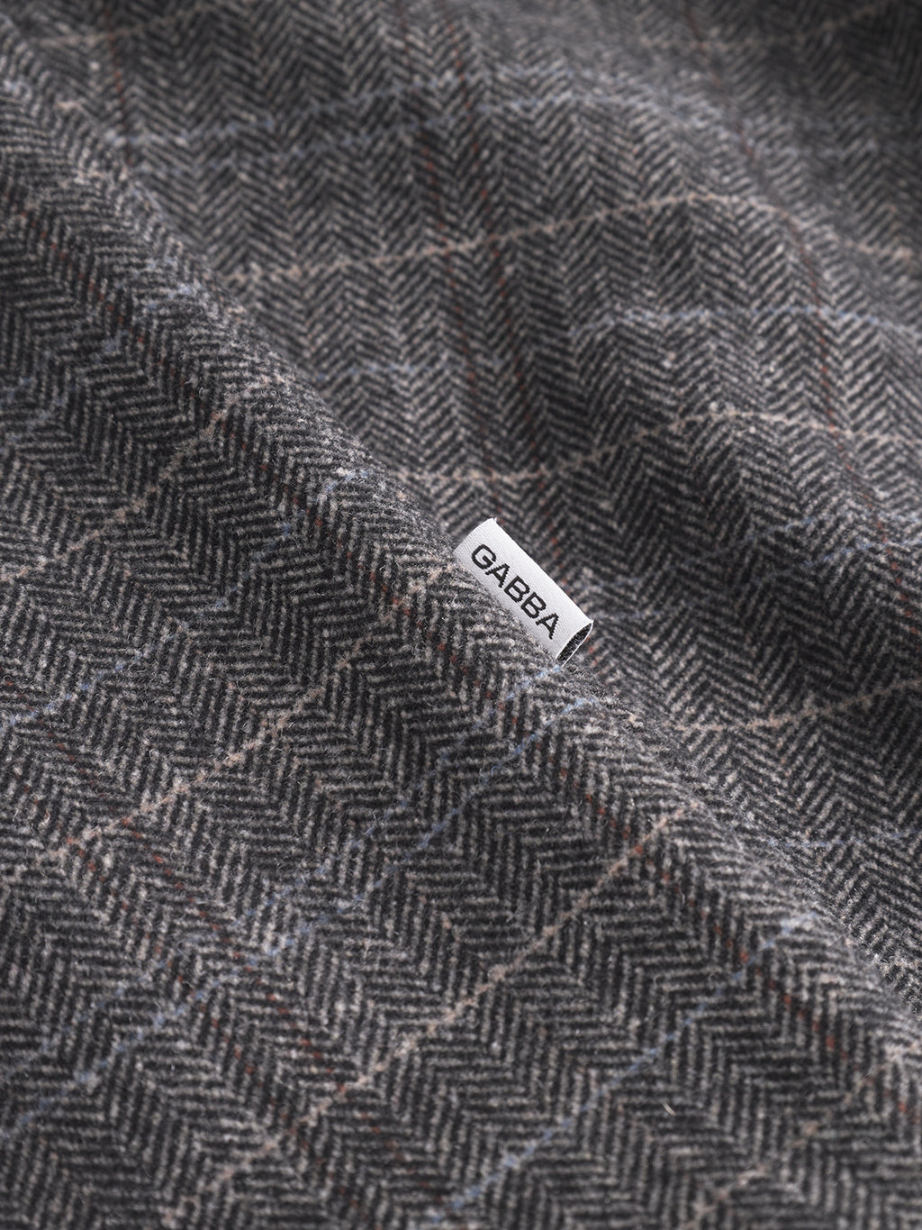 Close-up of the Flap Tishi - Brown Check fabric by Gabba, featuring a stylish check pattern and a small white tag labeled Gabba—ideal for a mens layering piece.
