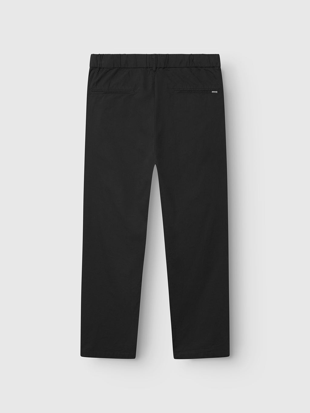 The Imola Kuadro - Black pants by Gabba are straight-leg with an elastic waistband, made from garment-dyed stretch fabric. Shown from the back, they feature a single zippered pocket and a clean, minimal design.