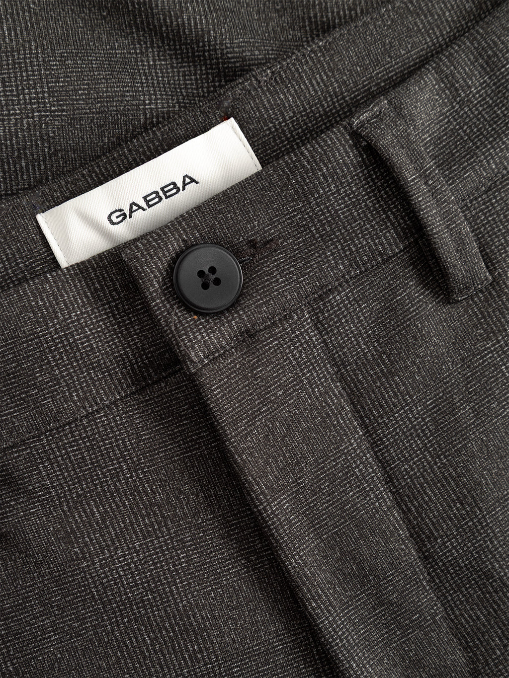 Close-up of Paul Nygo - Grey stretch trousers by Gabba, showcasing dark gray plaid fabric, black button, belt loops, tailored pockets, and a white Gabba label on the waistband.
