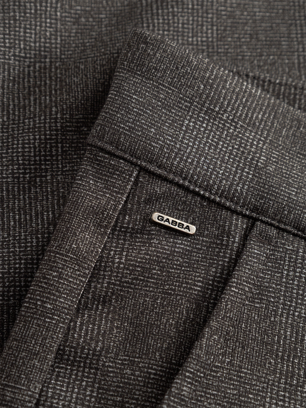 Close-up of Gabba’s Paul Nygo - Grey trousers in dark gray check with a subtle textured pattern, tailored pocket details, and a small metallic Gabba label above the pocket.