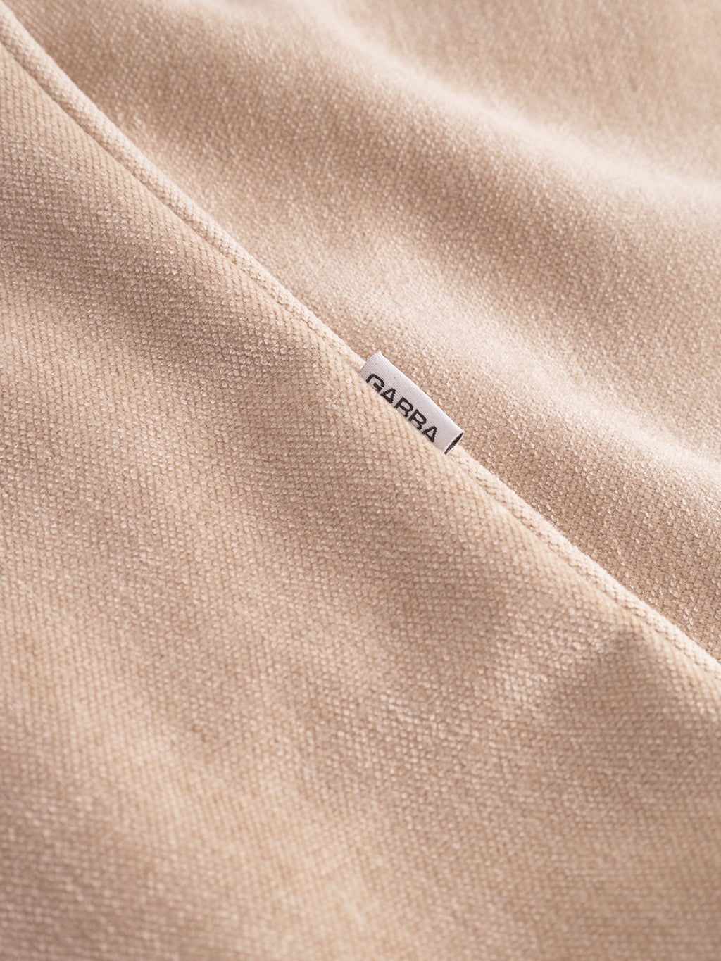 Close-up of Flap Velour - Lt. Sand by Gabba shows soft, textured fabric with a visible seam and a small white SABRA tag partially tucked in, highlighting the comfort typical of this regular-fit overshirt.