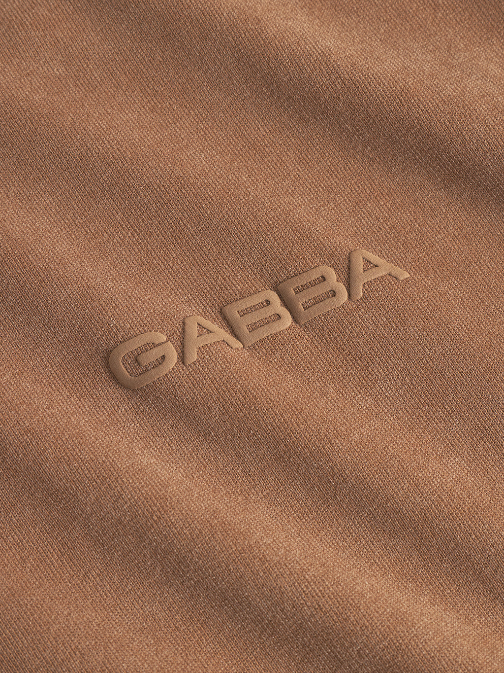 Close-up of Gabbas Nigel Wix Boxy Peso SS in bronze brown, featuring durable cotton jersey fabric and GABBA embossed in matching brown letters at the center.