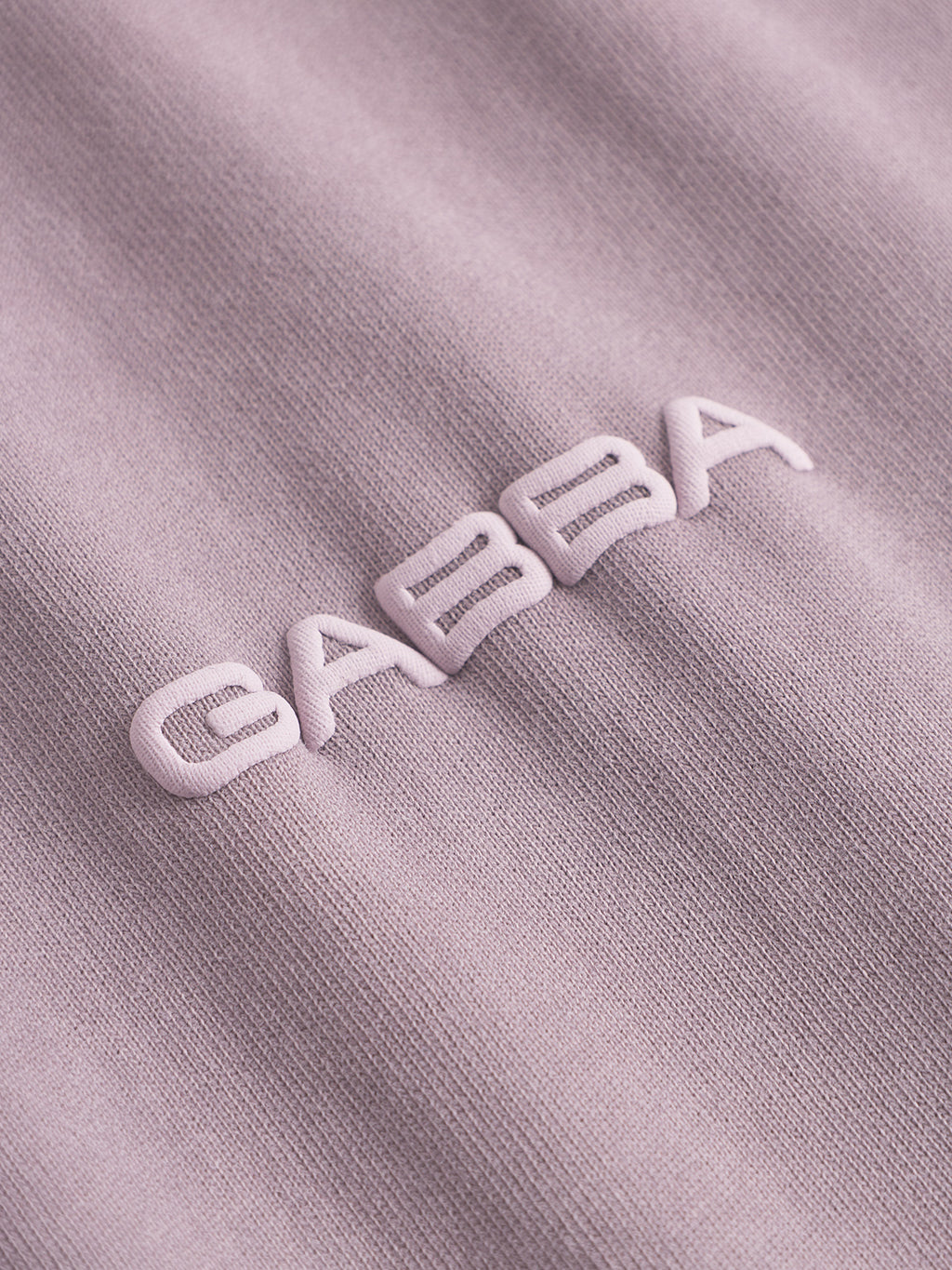 Close-up of the Nigel Wix Boxy Peso SS tee by Gabba in Dust Purple, featuring raised white embroidery spelling CARSA on soft cotton jersey.