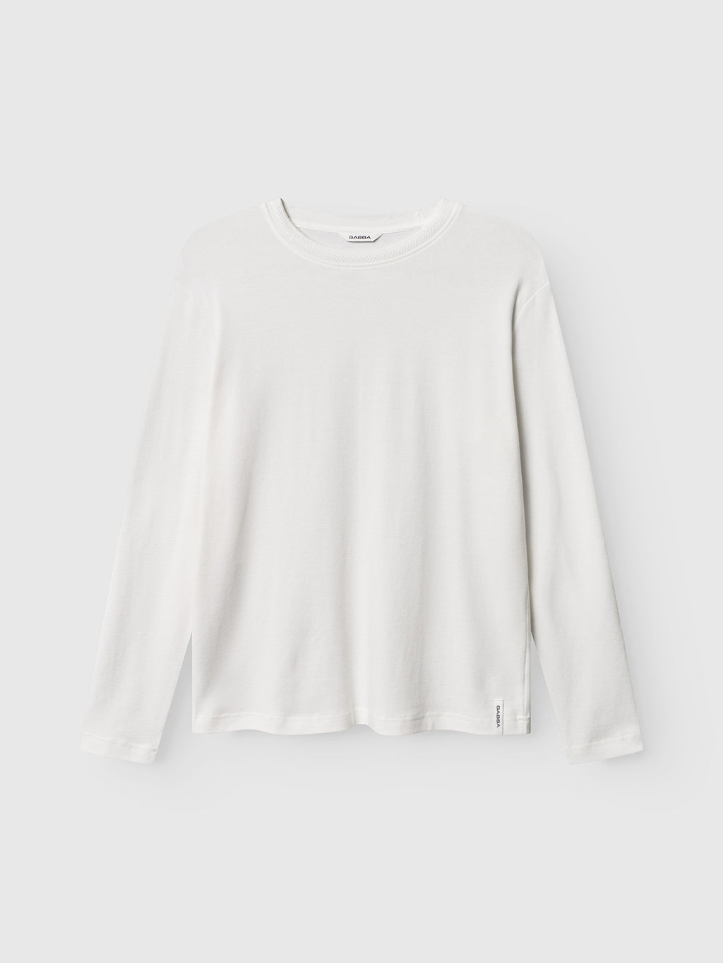 The Gabba Dune Brush LS in Off White is a plain long-sleeve tee featuring a crew neckline and regular fit, shown on a light gray background with visible cuffs and hem.
