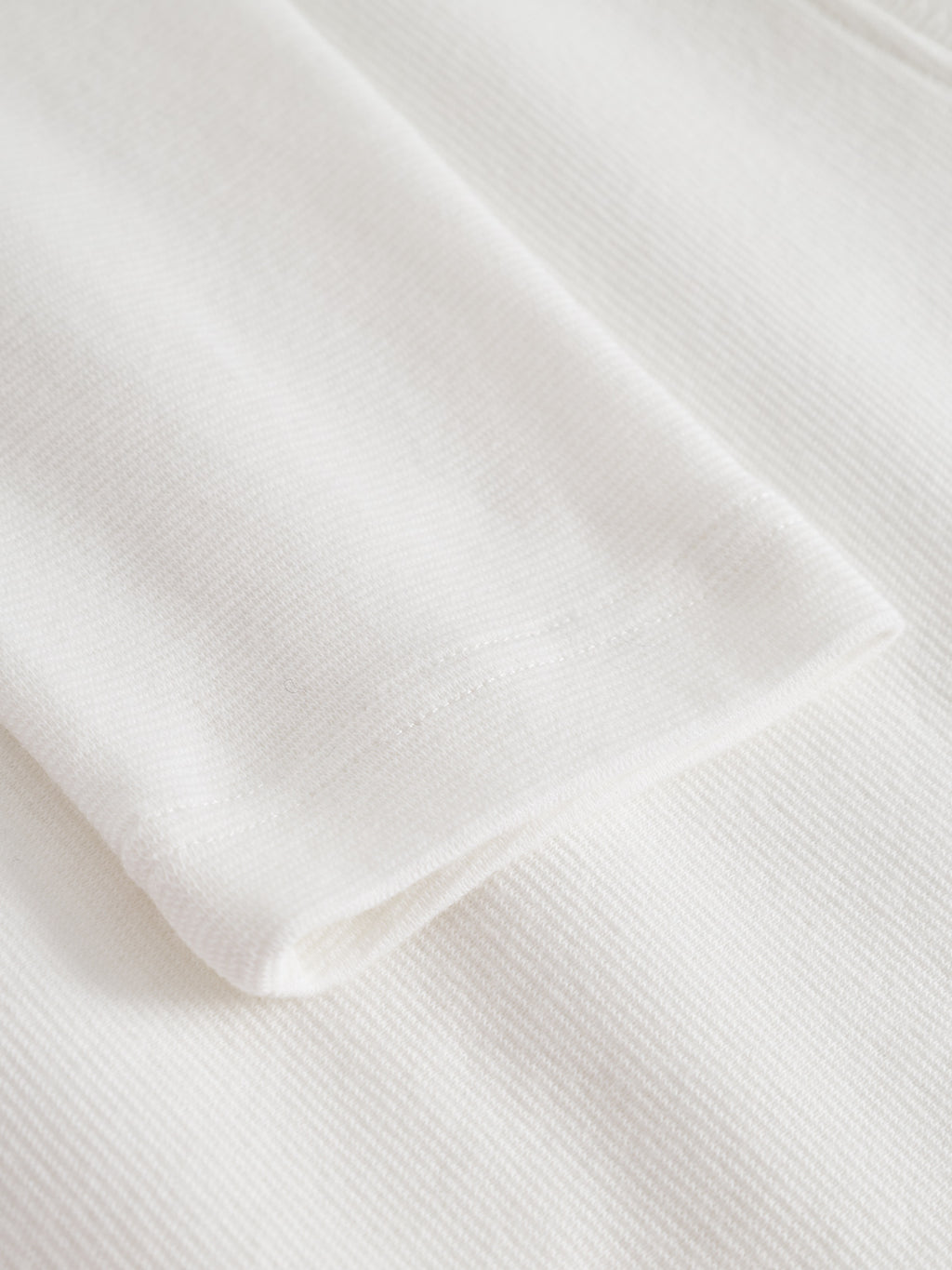 Close-up of the Gabba Dune Brush LS in Off White, showcasing its ribbed fabric texture and detailed cuff stitching, set against a matching background.