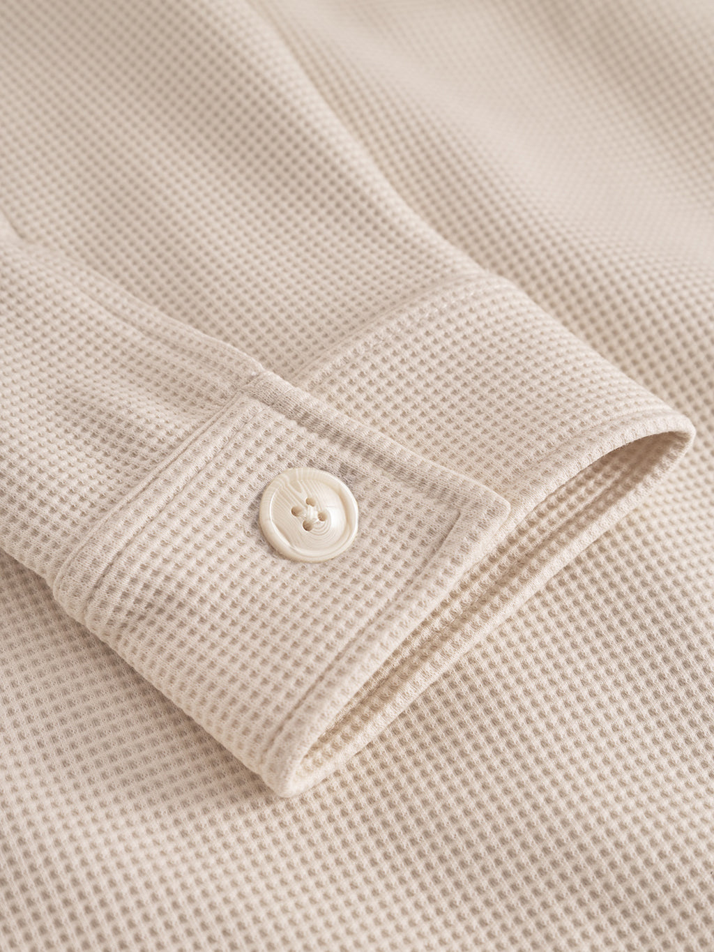 Close-up of a beige textured fabric with a button